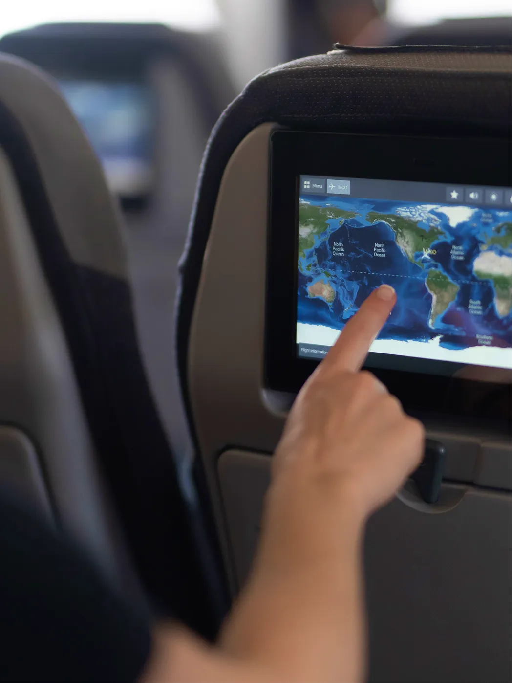 An airplane passenger interacting with seat display