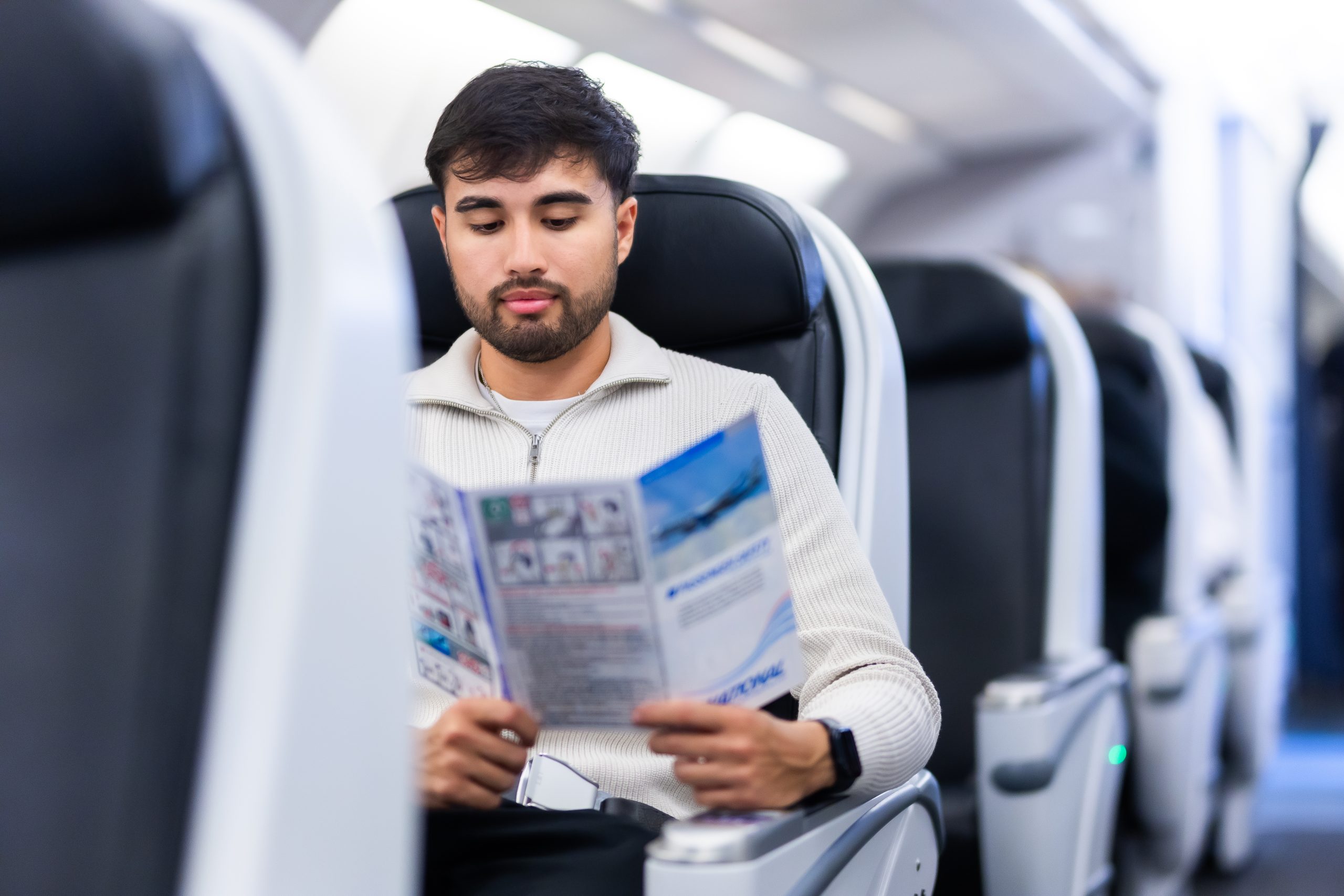 An airplane passenger reading a pamphlet