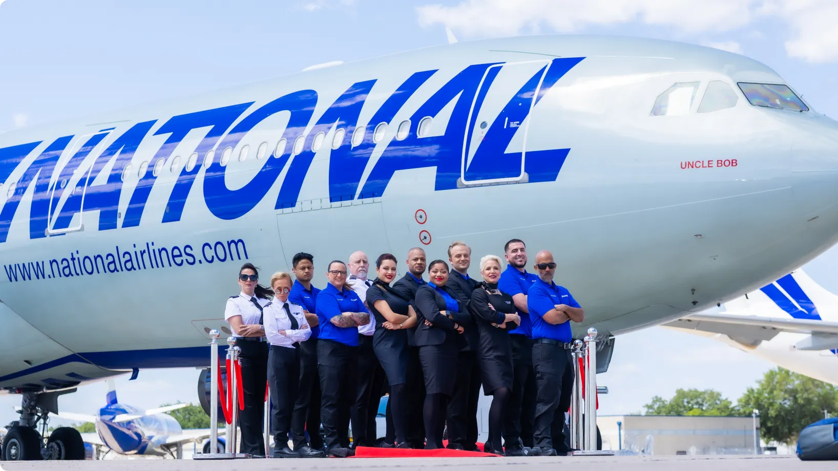 A group of workers posing beside an airplane