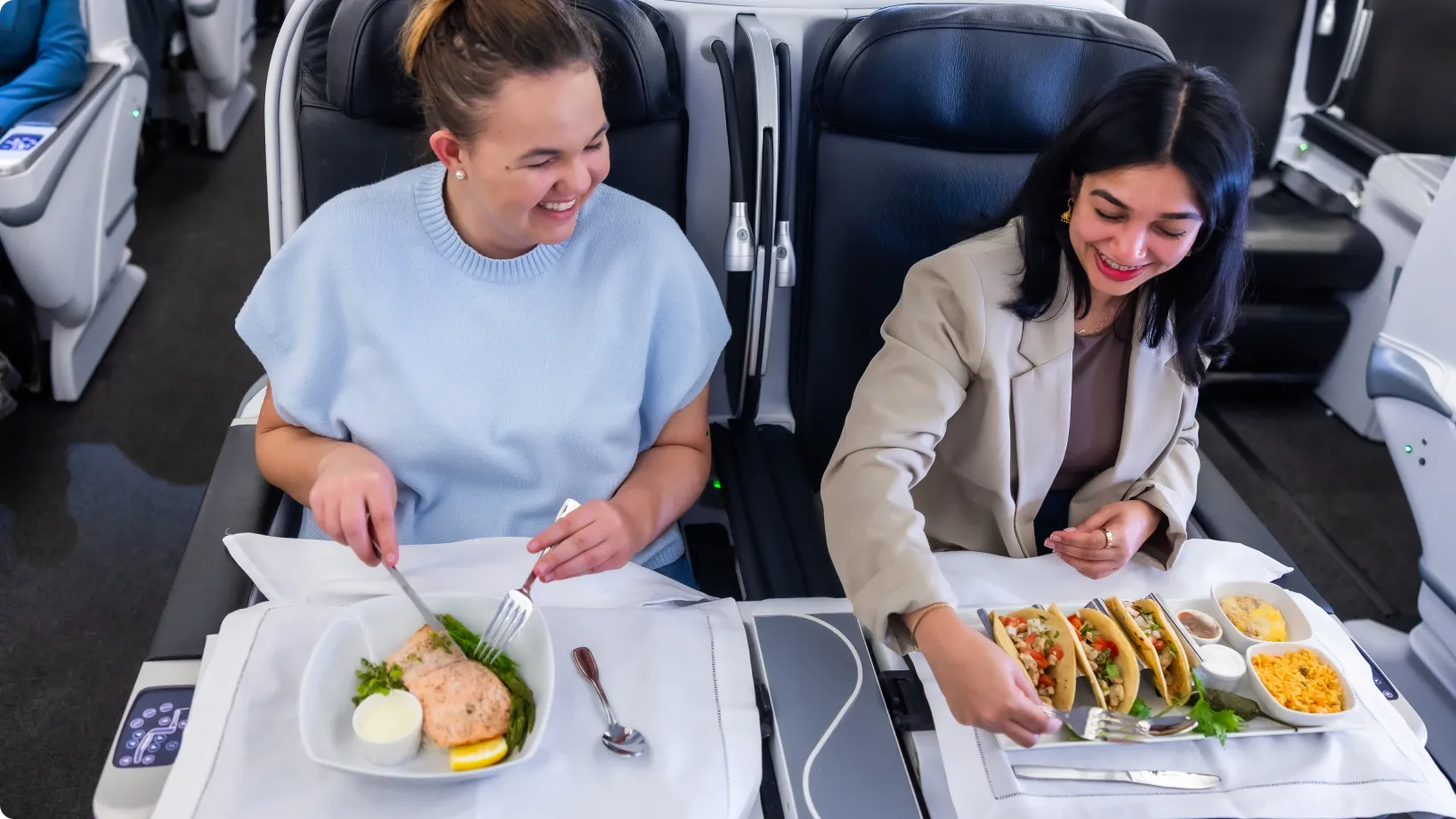 Two passengers eating on an airplane